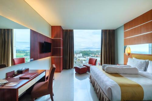 a hotel room with a bed and a desk and a desk at Grand Artos Hotel & Convention in Magelang