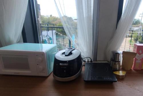 a microwave and a printer on a table with a window at Aewol Coast 34 in Jeju