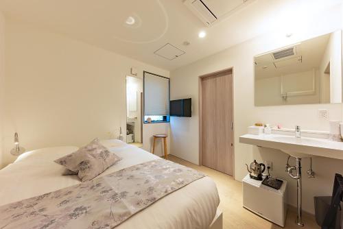 Habitación blanca con cama y lavabo en plat hostel keikyu sapporo ichiba en Sapporo
