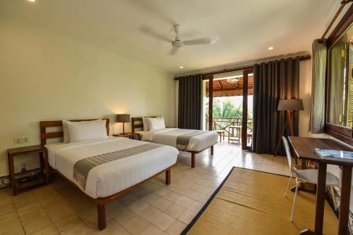 a hotel room with two beds and a balcony at Oh Battambang Boutique Hotel in Battambang