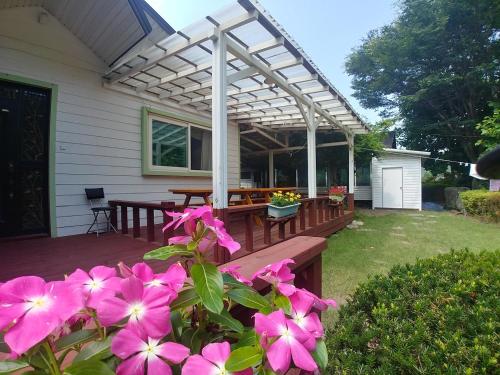 a wooden deck with a pergola and pink flowers at White House Over Hill in Yangyang