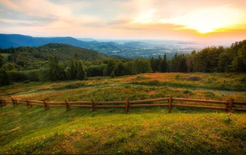 a wooden fence on top of a grassy hill at Domki pod brzozami Ustroń in Ustroń
