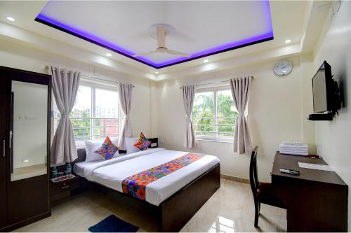 um quarto com uma cama com um tecto roxo em FabHotel Anchorage Inn em Calcutá