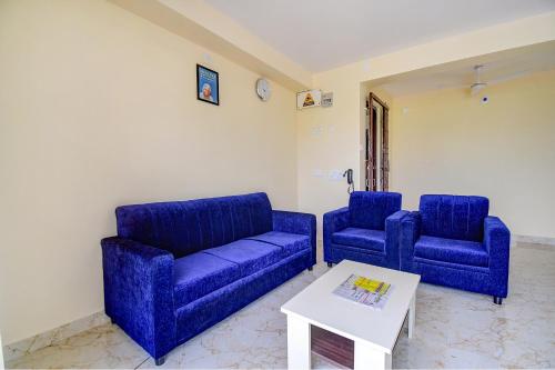 a living room with two blue couches and a table at FabHotel Anchorage Inn in Kolkata