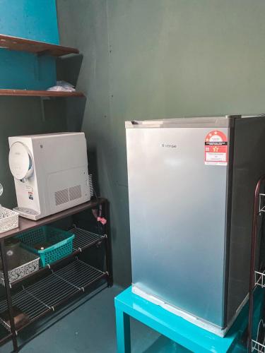a refrigerator next to a table and a microwave at PULAU INDAH HOMESTAY in Pulau Indah