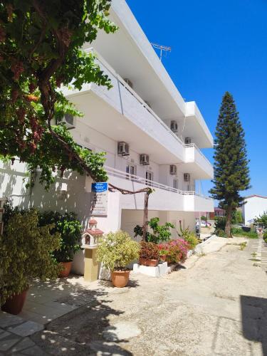 a white building with potted plants in front of it at Sofia Studios & Apartments in Georgioupolis