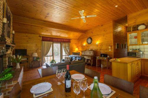 a kitchen and living room with a table with wine glasses at Silky Oak Cottage & Studio in Pokolbin