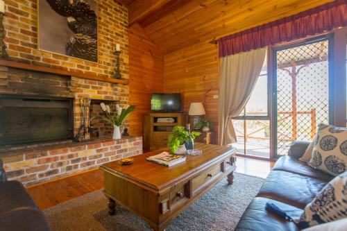 a living room with a couch and a tv at Silky Oak Cottage & Studio in Pokolbin