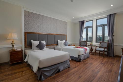 a hotel room with two beds and a desk at AVS Hotel Phu Quoc in Phu Quoc