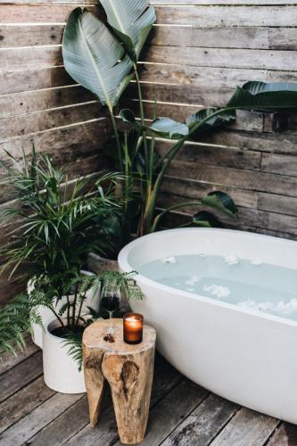 a bath tub sitting on a wooden deck with plants at Worrowing Jervis Bay in Huskisson