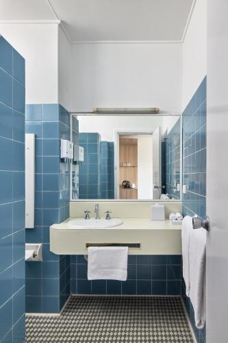 a blue tiled bathroom with a sink and a mirror at ibis Styles Tamworth in Tamworth