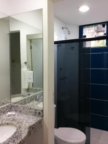 a bathroom with a toilet and a glass shower at Hotel Mundial in Itabuna