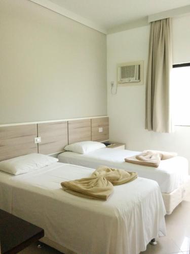 a room with two beds with towels on them at Hotel Mundial in Itabuna