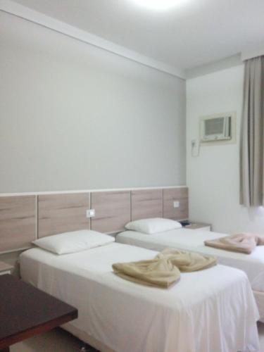 a hotel room with two beds with towels on them at Hotel Mundial in Itabuna