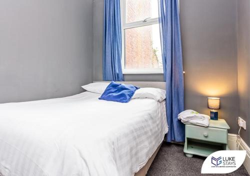 a bedroom with a bed with blue curtains and a window at Luke Stays - Brandling Street in Monkwearmouth