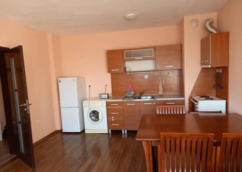 Il comprend une cuisine équipée d'un réfrigérateur blanc et d'une table. dans l'établissement Апартамент Романтика, à Varna