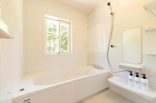 uma casa de banho branca com uma banheira e um lavatório em レジーナ石垣　ログテリアⅠ em Hirakubo