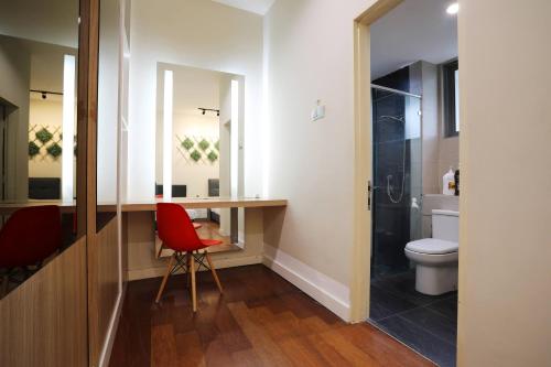 a bathroom with a toilet and a red chair at AJ Suites @ Loft Imago KK in Kota Kinabalu