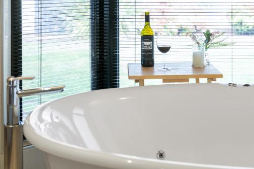 a white bath tub with a bottle of wine and glasses at Merlot Verdelho Townhouses in Penola