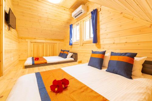 a bedroom with two beds in a log cabin at レジーナ石垣ログテリアⅡ in Hirakubo