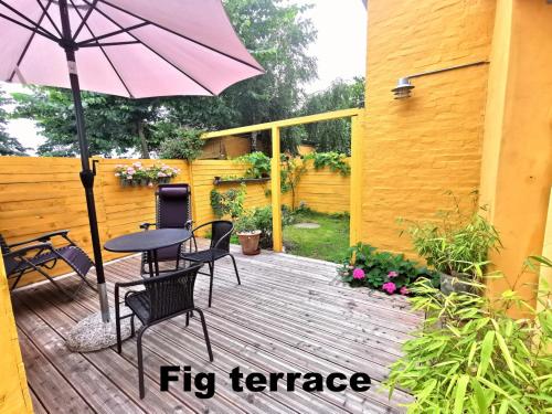 a patio with a table and chairs and an umbrella at The FIG Studio - "Den Gule Svane" Guest House - near Rønne & Beach in Rønne