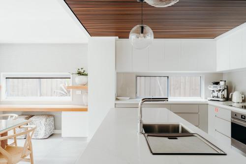 a kitchen with white cabinets and a black sink at KoKos Beach House 3 in Byron Bay