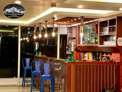 un bar avec tabourets bleus dans un restaurant dans l'établissement Mount Everest Hotel & Resort Nagarkot, à Nagarkot