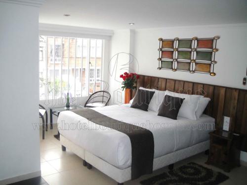 a bedroom with a large white bed and a window at Hotel Boutique Embajada de la Feria in Bogotá