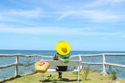 a person sitting on a bench looking at the ocean at Maayo San Remigio in San Remigio