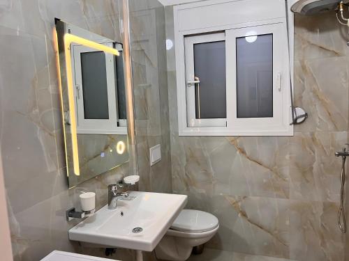a bathroom with a sink and a toilet and a mirror at Sunset Luxury Studios in Radhimë