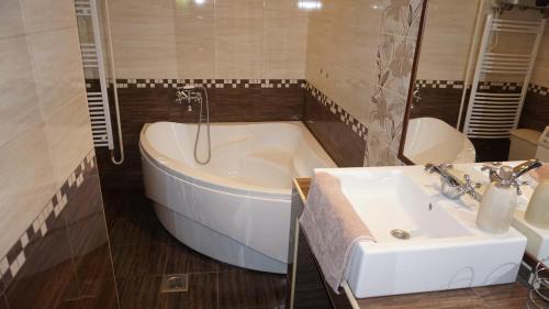 een badkamer met een bad, een wastafel en een toilet bij Édes Otthon Apartman in Gyula