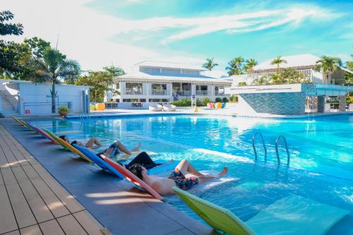 a group of people laying in chairs in a swimming pool at Maayo San Remigio in San Remigio