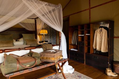 a bedroom with a bed with a dresser and a closet at Elewana Sand River Mara in Talek