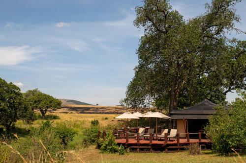 a gazebo with chairs and umbrellas in a field at Elewana Sand River Mara in Talek