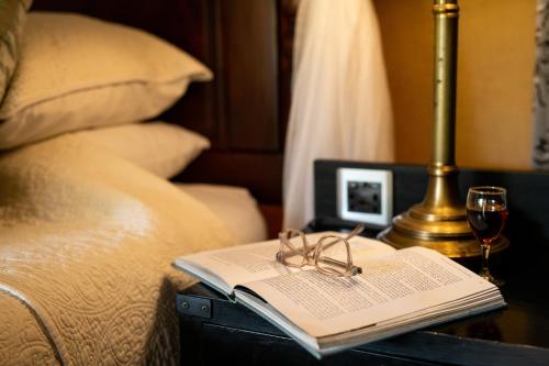 a book and glasses on a table next to a bed at Elewana Sand River Mara in Talek
