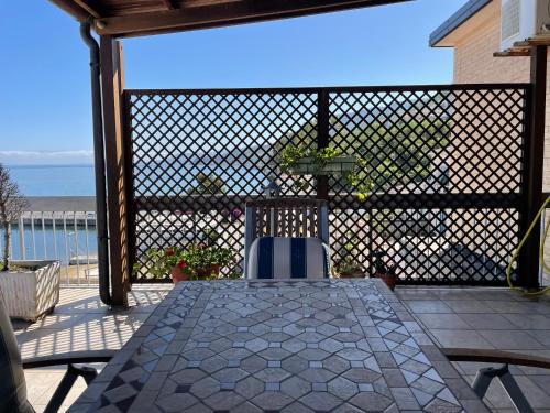 un patio con mesa, sillas y el océano en Attico con terrazza sul porticciolo turistico di Vibo Marina, en Vibo Valentia Marina
