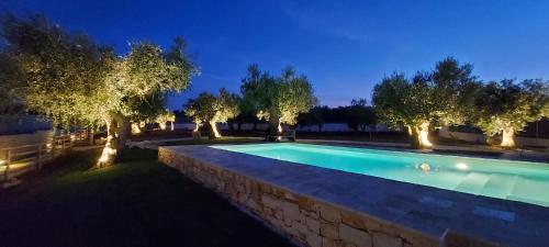 a swimming pool in a yard with trees at night at Trulli Lisanna - Exclusive Trulli With Private Pool in Antonelli