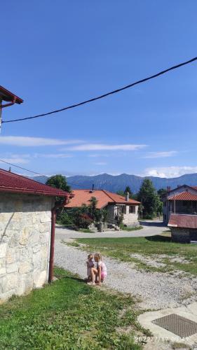 two girls sitting on the gravel in a yard at Holiday Farmhouse Skvor in Robidišče