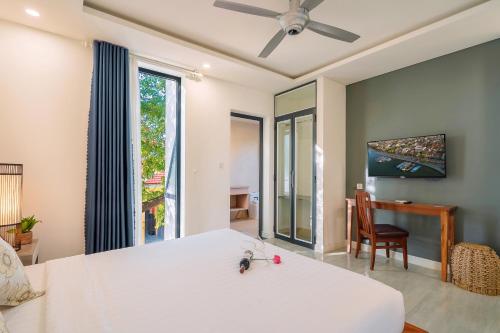 a bedroom with a large white bed and a desk at Aroma Garden Suites Hoi An in Hoi An