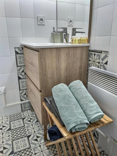 La salle de bains est pourvue d'un lavabo et de serviettes sur un banc. dans l'établissement Le Temps Suspendu - Au cœur d'Albi, à Albi