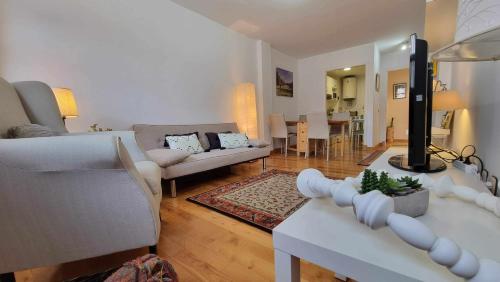 sala de estar con muebles blancos y comedor en Apartamento El Faro de Llanes, en Llanes