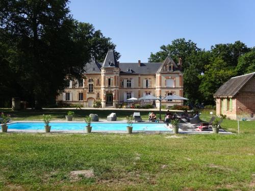 une grande maison avec une piscine devant dans l'établissement Château Les Villiers - Au cœur de la Sologne, à Villeny