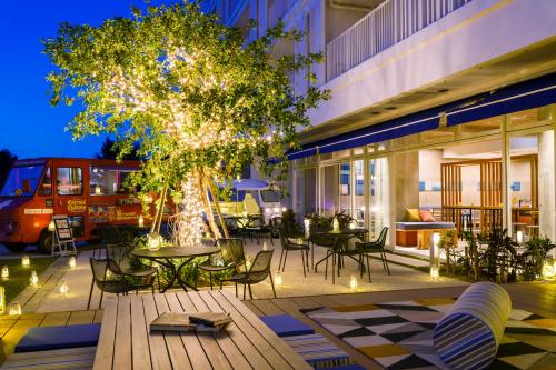 a patio with tables and chairs and a tree at BEB5 Okinawa Seragaki by Hoshino Resorts in Onna