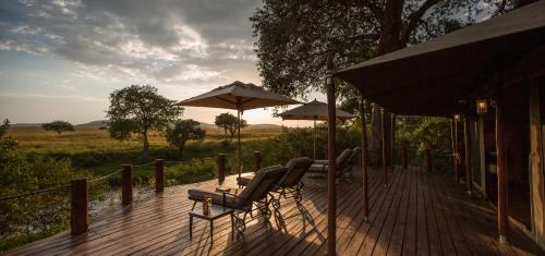 a deck with chairs and umbrellas on a house at Elewana Sand River Mara in Talek