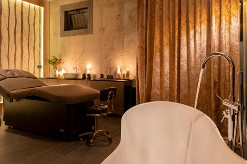 a bathroom with a bath tub and a chair and a sink at Caryńska Resort & SPA in Lutowiska