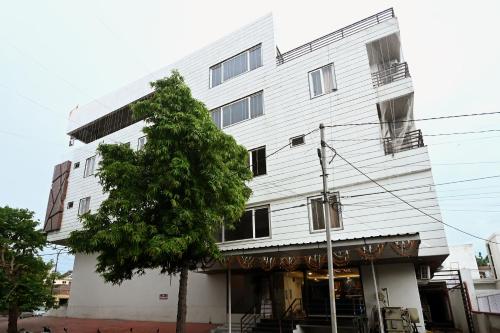 a white building with a tree in front of it at Hotel Hallmark By THC Group in Kota