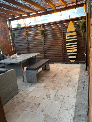 a patio with a table and a surfboard on a wall at case à roches in Saint-Gilles les Bains