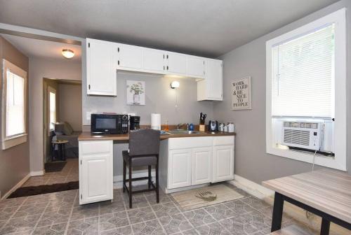 a kitchen with white cabinets and a table and a microwave at CHERRY ST LITTLE LOVE HOUSE* SHOP*DINE* RT 66*EXPO CENTER*BOK*DOWNTOWN in Tulsa
