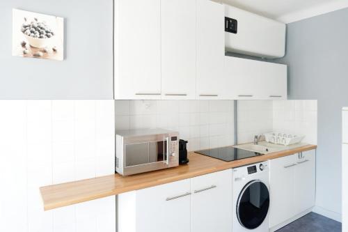 Il comprend une cuisine blanche équipée d'un four micro-ondes et d'un lave-linge/sèche-linge. dans l'établissement Appartement Saint-jean-de-luz, à Saint-Jean-de-Luz