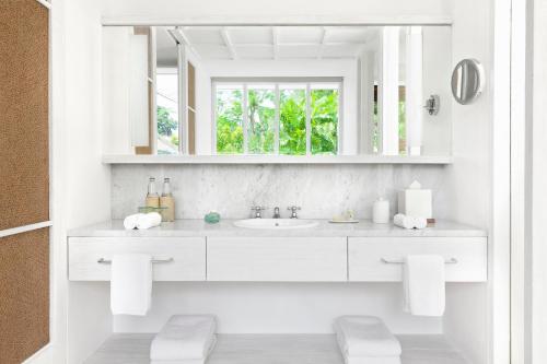 Baño blanco con lavabo y espejo en COMO Uma Ubud en Ubud